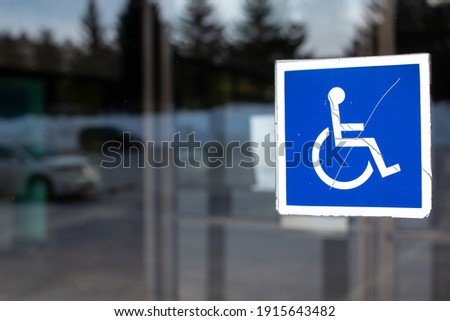 The International Symbol of Access icon, a blue square with a white graphic wheel chair and person, in a window in London Ontario Canada, February 2021.  