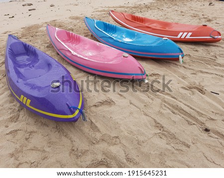Rows of boats designed for surfing kayaking are on the shore. This item is made of glass composite (a mixture of carbon fiber, Kevlar and fiberglass) or rotomolded plastic.