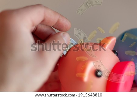 A man's hand inserts a coin into a piggy bank