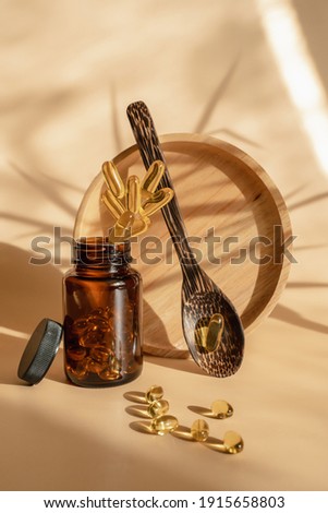 The pills fall into the jar. Levitation style. Omega 3 tablets on a beige background. Spoon with omega 3 capsules