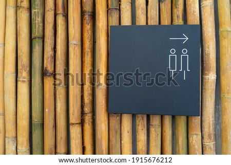 Label of symbol for the toilet for men and women on black background,Direction and navigation signs in the bamboo tube wall for lost and found and WC restroom in the building.