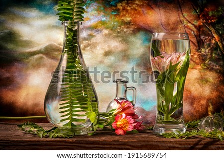Cut flowers and tropical plants in a glass of water on a barn wood table 