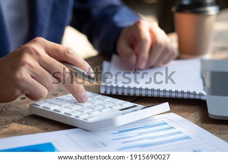 Close up businessman hand using calculator and working with  laptop calculate about finance accounting at coffeeshop outdor.finance accounting concept Royalty-Free Stock Photo #1915690027