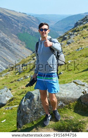 Tourist standing on the rock over the valley with lake and mountains in the background in Wicklow National Park.