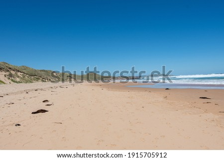 beach with red rock and blue sky and ocean and waves