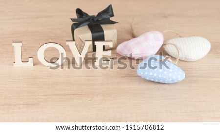 word Love from wooden letters with colorful fabric hearts on a wood background. Happy Valentines Day