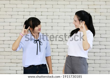 Two young and beautiful Asain women learning and displaying the skill of deaf people communication, hand and sign language