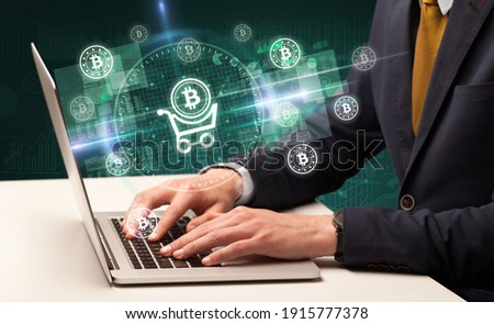 business hand working in stock market with shopping cart with bitcoin icons coming out from laptop screen