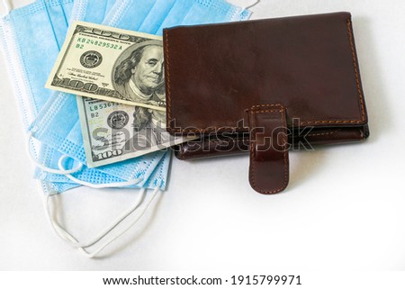 the concept of coronavirus and business on medical masks is a wallet with hundred dollar bills. High quality photo