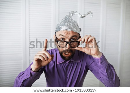 Bearded funny man in cap of aluminum foil. Concept art phobias. Conspiracy theory. Conspiracy. Insanity. Royalty-Free Stock Photo #1915803139