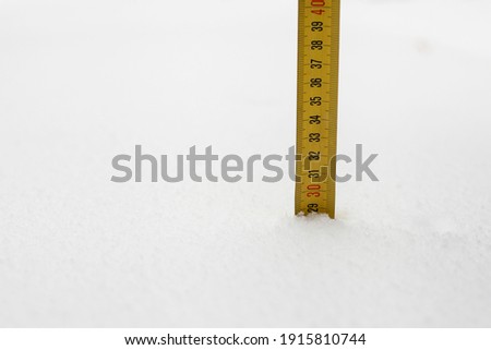Measuring the snow level with a mechanical tape measure.  Royalty-Free Stock Photo #1915810744