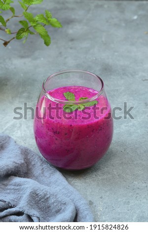 A glass of dragon fruit juice on the concrete table 
