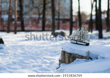 Model of a frigateon a snowy tree stump.