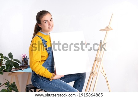 Female artist holding blank canvas facing camera