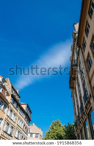 Ultra low angle view of French alsatian timbered house and Haussmannian architecture with clear blue sky in between them