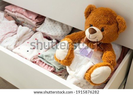 Pcture of a brown teddy bear with diaper on sitting in baby bed Royalty-Free Stock Photo #1915876282