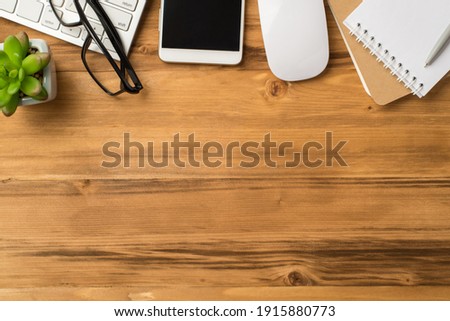 Overhead flatlay layout view photo of office items notebook pen eyeglasses cellphone on light color wooden backdrop with blank empty space