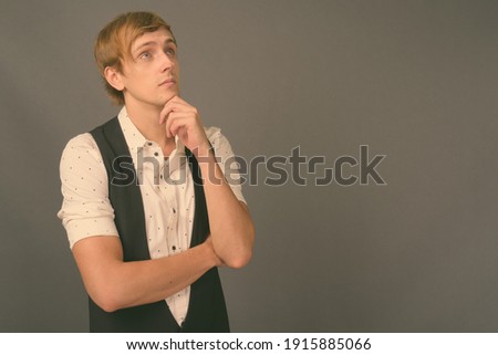 Young handsome businessman with blond hair against gray background