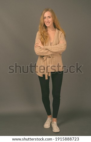 Young beautiful woman with blond hair against gray background