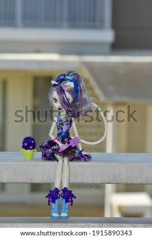 Close-up portrait of a human figurine with purple hair sitting on a white surface
