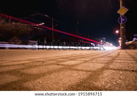 Red streams of cars at night. View from ground level. Asphalt, road signs. Trail from the movement of cars.