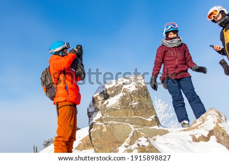 A group of tourists in the mountains in winter. A man takes a photo of his friends at the top of a mountain on a clear frosty morning