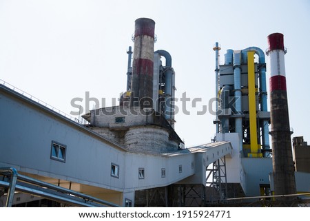 Plant for the production of cement and building mixes. Factory structures, pipes against the blue sky