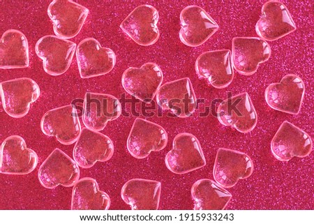 many transparent glass hearts on red sparkling background for valentine's holiday