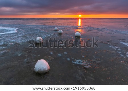 Beautiful sunset over the Bay of Gdansk in Jastarnia. Natural snow balls on the beach. Winter landscape. Poland.