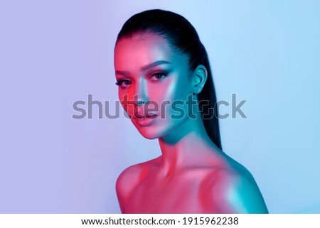 High fashion model metal silver lips and face woman in colorful bright neon UV blue and purple lights, posing in studio, beautiful girl, glowing makeup, colorful makeup. Glitter Bright Neon Makeup Royalty-Free Stock Photo #1915962238