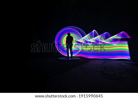 one person standing against beautiful yellow and purple circle light painting as the backdrop
