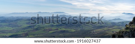 A panorama landscape of rolling hills and blue mountain chains Royalty-Free Stock Photo #1916027437