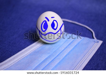 angry indignant egg in a protective mask on a medical bandage close-up on denim