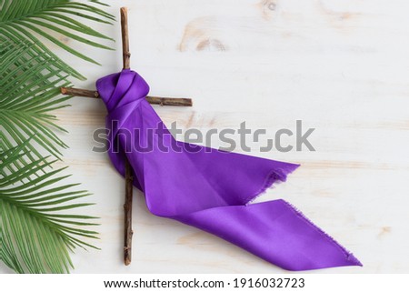 cross with purple sash and palms on white wood Royalty-Free Stock Photo #1916032723