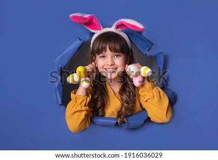  Girl at Easter with bunny ears and painted eggs