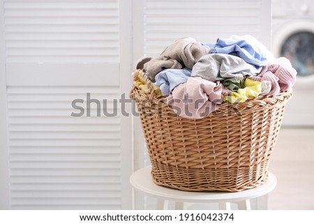 Wicker basket with dirty laundry indoors, space for text Royalty-Free Stock Photo #1916042374