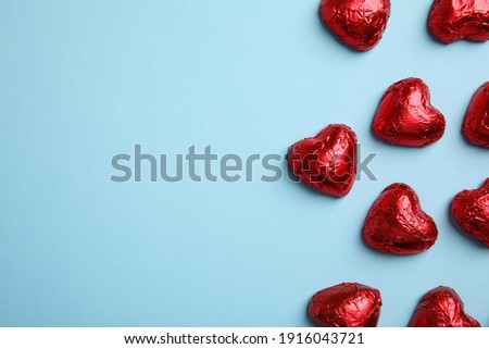 Heart shaped chocolate candies on light blue background, flat lay with space for text. Valentine's day treat