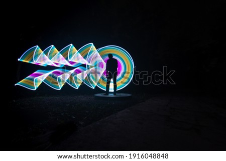 one person standing against beautiful yellow and pink circle light painting as the backdrop