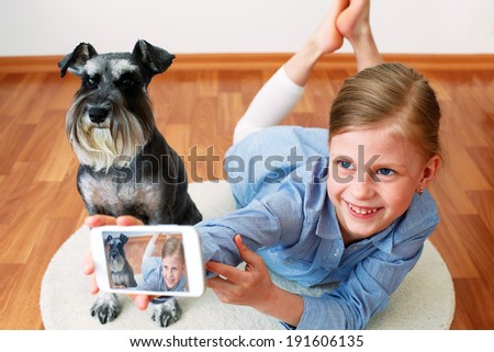  Little girl taking photo of herself and her dog with mobile phone camera 