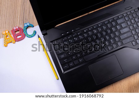 ABC programming language. Laptop on wooden table background. Alphabet on white empty copy space page near illuminating color pencil. Electronic online study. High quality photo