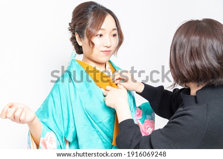 A woman who has a kimono dressed and a woman who is a dresser