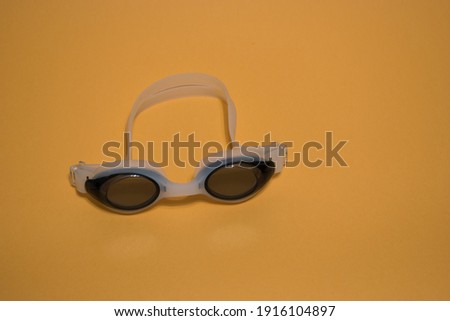 Professional white glasses for swimming isolated on a yellow background.White swim goggles.
