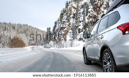 Suv car with rooftop cargo carrier trunk stay on roadside of winter road. Family trip to ski resort. Winter holidays adventure. car on winter road Royalty-Free Stock Photo #1916113885