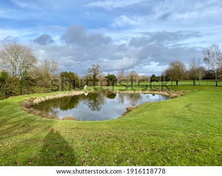 Lake at the edge of a golf course fairway, in the British winter.