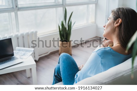 Business woman in blue shirt chatting,talking in mobile phone.Remote work at home office sitting on couch.Messaging,dating,meeting in social net.Relax in fasionable appartment.Covid-19 self isolation.