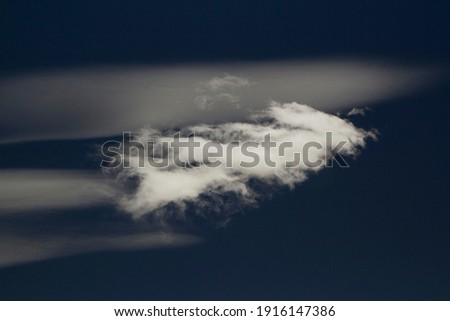 Minimalist cloudscape. Single white cloud in the deep blue sky. 