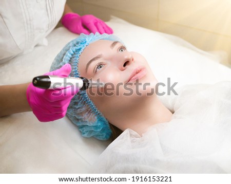Micro needling therapy. Professional cosmetologist is doing procedure of microneedling. Fractional Needle mesotherapy with dermapen close up. Beauty salon, cosmetology clinic. Face Skin Care treatment Royalty-Free Stock Photo #1916153221