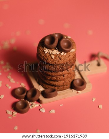 oatmeal cookies on a pink background, sprinkled with oatmeal and chocolate chips. a sweet snack, pastry, bakery, beautiful bright food photo