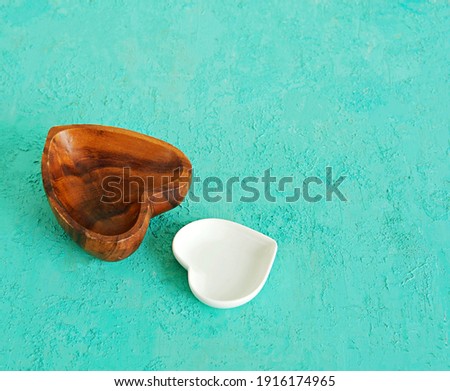 Empty wooden bowl in the shape of a heart on a turquoise background. Valentine's day concept.