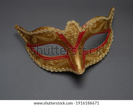 Traditional golden carnival Venetian mask with red ornament on a black background. Preparation for the Brazilian Festival and Mardi Gras.